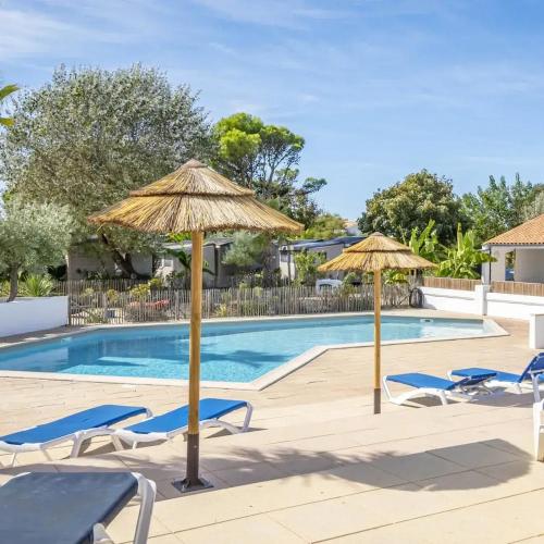 a swimming pool with two umbrellas and chairs and a swimming pool at Camping A la Corniche - Maeva in Angoulins-sur-Mer