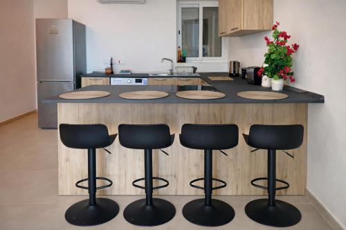 a kitchen with a counter with four bar stools at Comfortable ! Stylish ! Fully Air Conditioned ! in Sannat