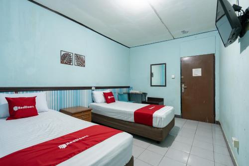 a hotel room with two beds and a television at RedDoorz Syariah near Pasar Pagi Samarinda in Samarinda