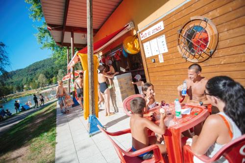 a group of people sitting at a table at a restaurant at Camping Base de Loisirs du Lac de la Moselotte in Saulxures-sur-Moselotte