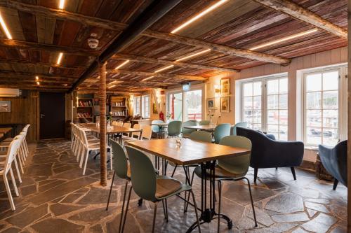 a restaurant with tables and chairs and windows at Kuringen Brygge Hotel and Restaurant in Refsnes
