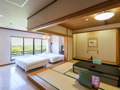 a bedroom with two beds and a desk and a table at Ikoi no mura Notohanto in Shika