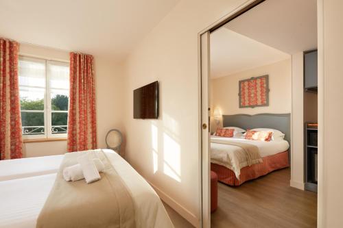 a hotel room with a bed and a mirror at Relais des Trois Châteaux Hôtel-Restaurant - Teritoria in Cour-Cheverny