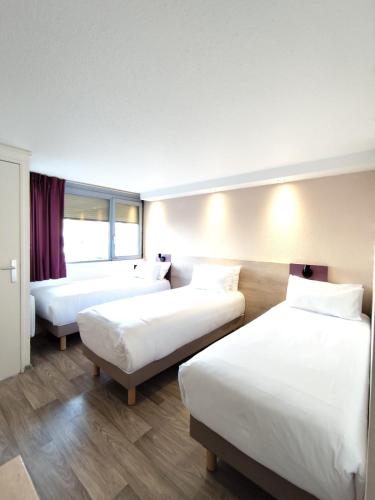 a hotel room with three beds and a window at Kyriad Meaux Sud Nanteuil Les Meaux in Nanteuil-lès-Meaux
