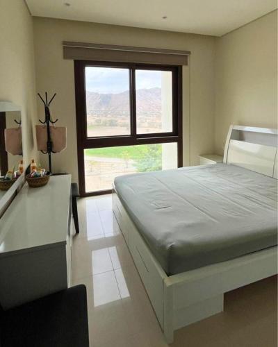 a bedroom with a large bed and a window at Sifa Golf & Beach Escape in As Sīfah