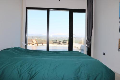 a bedroom with a green bed and a large window at Villa Al Fianco in Petacciato
