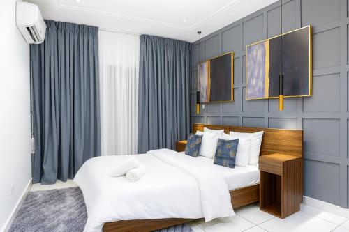 a bedroom with a large white bed and blue walls at Oasis Apartments Gh by Embassy Gardens in Accra