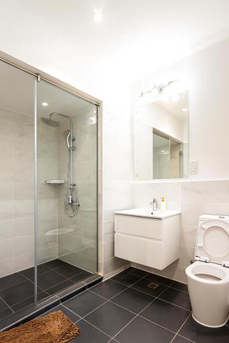 a bathroom with a shower and a toilet and a sink at Oasis Apartments Gh by Embassy Gardens in Accra