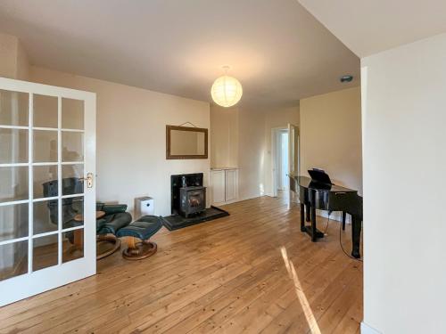 an empty living room with a table and a piano at Holly Croft in Drem