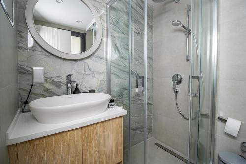 a bathroom with a sink and a shower with a mirror at Mykonos Holiday Homes in Kyrenia