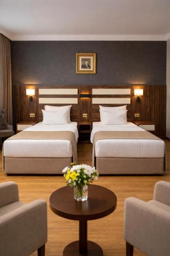 a hotel room with two beds and a table with flowers at Akgün Hotel Laleli Istanbul in Istanbul