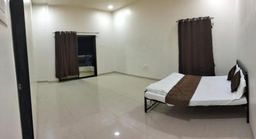 a bedroom with a bed and a window with curtains at Mannat Bungalow in Amrāvati