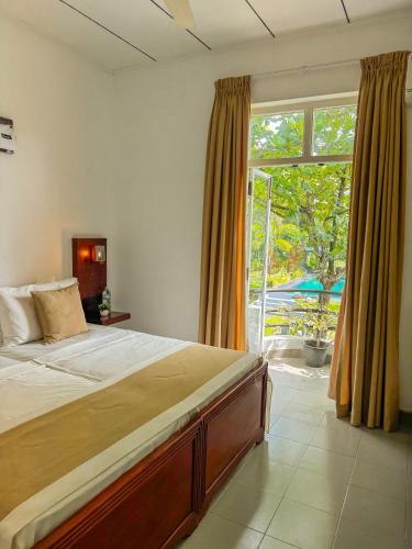 a bedroom with a large bed and a large window at Villa Sarakkuwa in Pamunugama
