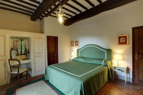a bedroom with a green bed and a chair at Villa Le Barone in Panzano