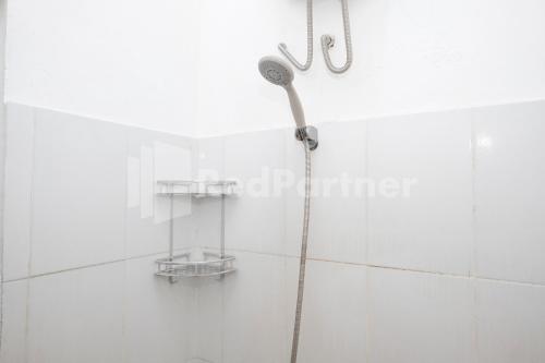 a shower in a white tiled bathroom at Katup Guest House Syariah Mitra RedDoorz in Yogyakarta
