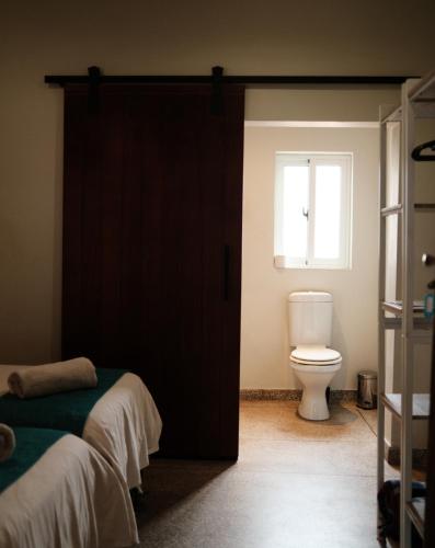 a bathroom with a door with a toilet and a window at Jollyboys Backpackers and Camp in Livingstone