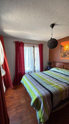 a bedroom with a bed and red curtains at Cabaña Las Cruces in Las Cruces