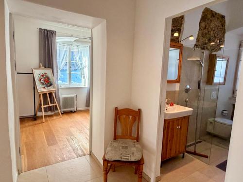 a bathroom with a chair and a sink and a mirror at FeWo Altes Doktorhaus in Berchtesgaden