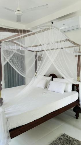 a bedroom with a canopy bed with white sheets and pillows at Jameens Residence in Ambalangoda