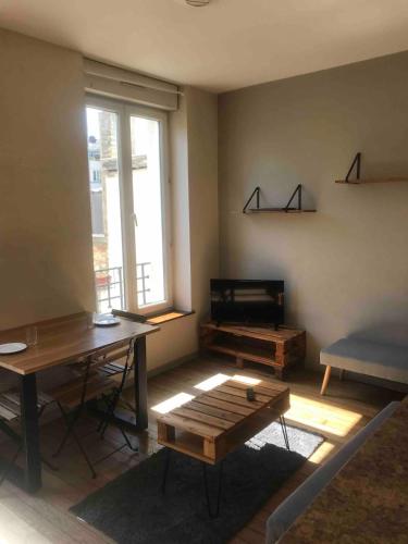 Appartement hyper centre في رانس: غرفة معيشة بها طاولة ومقعد ونافذة
