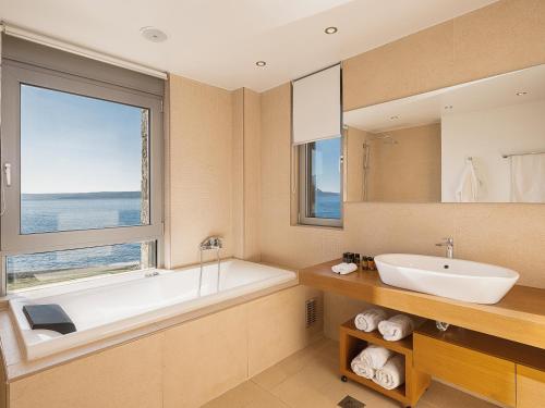 a bathroom with a tub and a sink and a window at SK Place Luxury Seafront Villas Chania in Almyrida