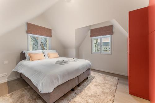 a bedroom with a large bed with white sheets and orange pillows at stijlvol appt met adembenemend uitzicht op het centrum van Ieper in Ieper