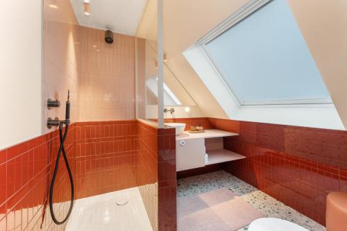 a bathroom with red tile and a shower with a window at stijlvol appt met adembenemend uitzicht op het centrum van Ieper in Ieper