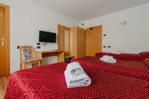 a hotel room with two beds with red sheets and towels at Hotel Spera in Strigno