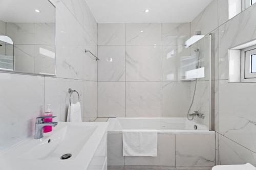 a white bathroom with a tub and a sink at Levanda Hills Haven in Protaras in Paralimni