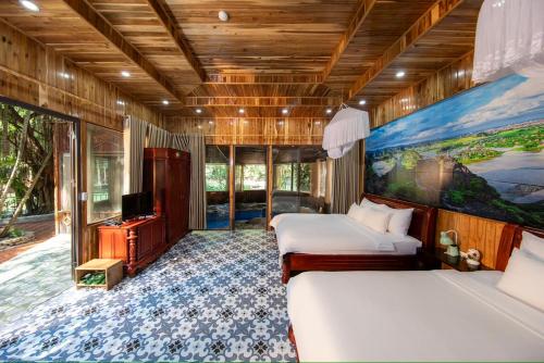 a bedroom with two beds and a television in it at Hang Mua Ecolodge in Ninh Binh
