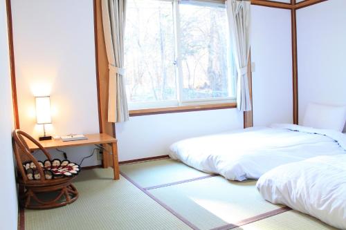a bedroom with a bed and a desk and a window at 彩の宿月屋 in Yamanakako