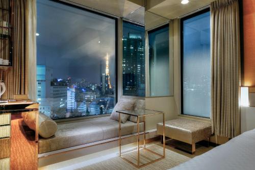 a bedroom with a window seat with a view of a city at Candeo Hotels Tokyo Roppongi in Tokyo