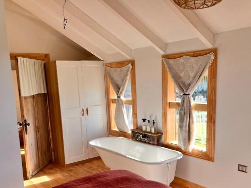 a white bath tub in a room with windows at Refugio del Sur, Escapada in Llanquihue