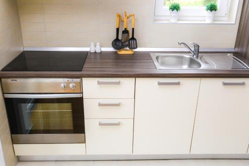 a kitchen with white cabinets and a sink at Summer Breeze Pool Apartments in Novalja