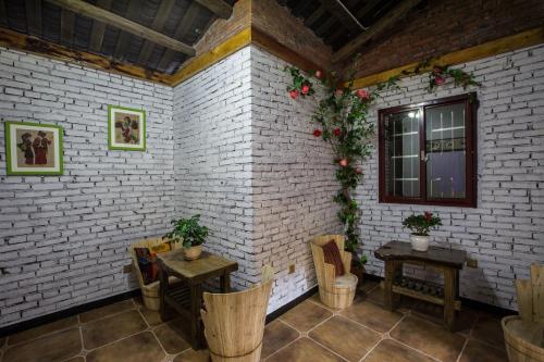 a room with two tables and chairs and a brick wall at Chong Chong Guesthouse in Zhangjiajie