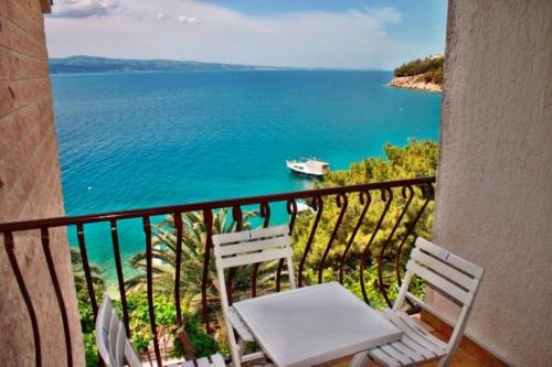 a balcony with two chairs and a boat in the water at 230 MESTRO in Stanići