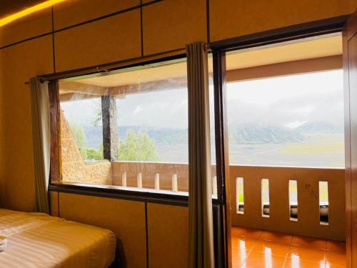 a bedroom with a large window with a view at Cemara Indah Hotel in Bromo