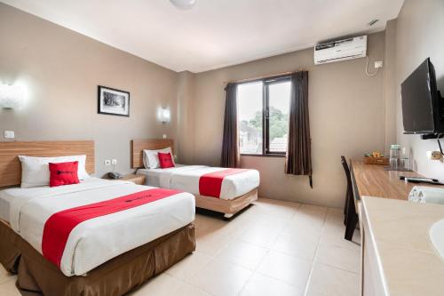 a hotel room with two beds and a television at RedDoorz Plus at Hotel Ulin Samarinda in Samarinda