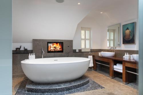 a large white bath tub in a bathroom with a fireplace at Linthwaite House Hotel in Bowness-on-Windermere