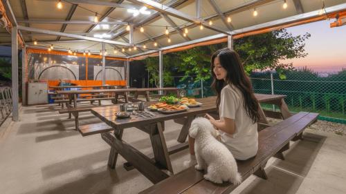 a woman sitting at a picnic table with a dog at Samcheok Greenhyang Pension in Samcheok