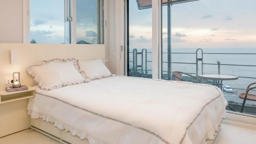 a bedroom with a bed and a view of the ocean at Yeosu Eoneumeosjinnal Pension in Yeosu