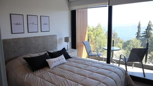 a bedroom with a large bed and a large window at Amanecer del lago in San Carlos de Bariloche