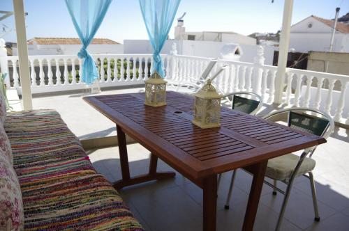 Eleni Boutique Apartment في ليندوس: طاولة خشبية على شرفة مع كراسي وطاولة