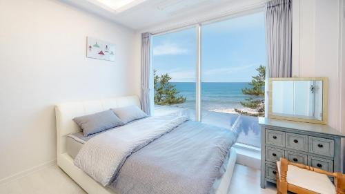 a bedroom with a bed and a large window with the ocean at Pohang Playbeach Poolvilla in Pohang
