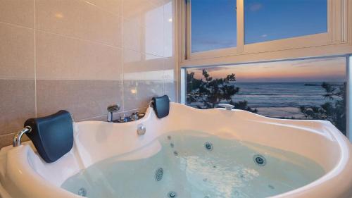 a bath tub in a bathroom with a window at Pohang Playbeach Poolvilla in Pohang