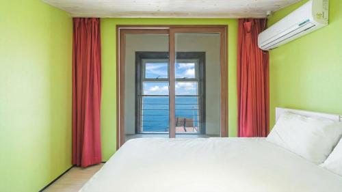 a bedroom with a bed and a window with the ocean at Geojedo Pilos Ocean View Pension in Geoje