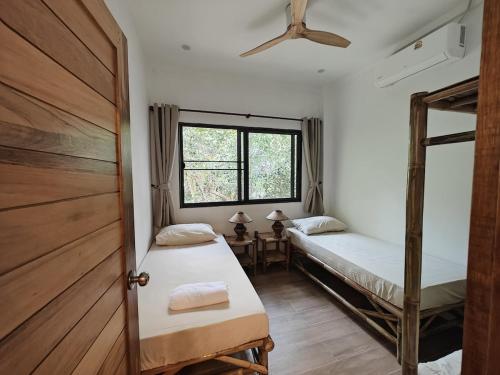 two beds in a room with a door and a window at Ganesha Mouse House in Ko Phangan