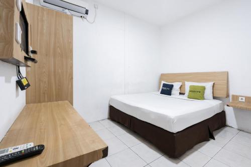 a bedroom with a bed and a television in it at Urbanview Hotel Cozy Samarinda by RedDoorz in Samarinda