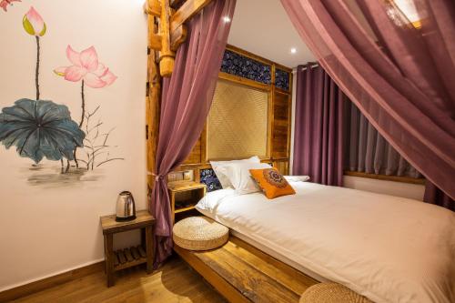 a bedroom with a bed and a window with purple curtains at Chong Chong Guesthouse in Zhangjiajie