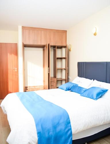 a bedroom with a large bed with blue pillows at Zinari Comfort Homes in Nakuru